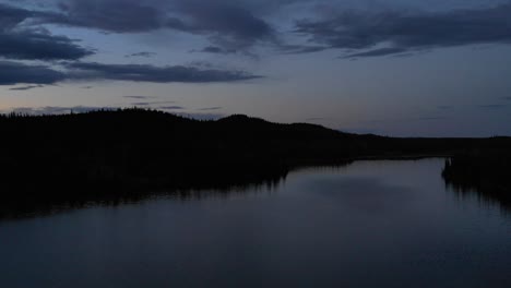 4K-footage-of-drone-flying-over-dark-waters-and-approaching-lakeshore-at-dusk