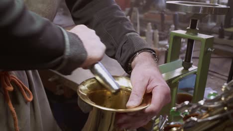 Skilled-Instrument-maker-repairing-dents-in-golden-saxophone-bell-with-specialized-tool-by-hand