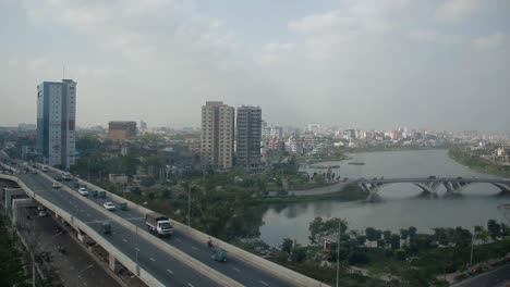 Dhaka-Stadt-Schöne-Draufsicht-Schwenk-Von-Rechts-Nach-Links,-Weiter-Himmel-Mit-Stadtbrücke,-See,-Gebäuden-Und-Autoverkehr