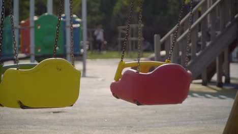 Einsame-Rote-Schaukel-Mit-Kettenbefestigungen-Auf-Dem-Spielplatz-An-Einem-Sonnigen-Tag