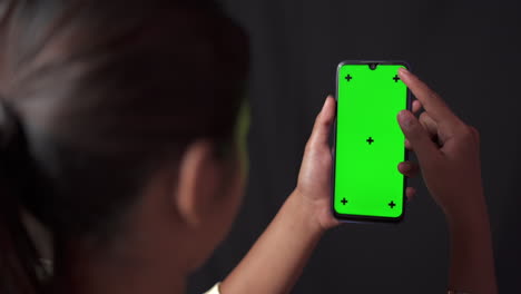 Greenscreen-Chroma-Key-Smartphone-In-Den-Händen-Eines-Mädchens-Im-Raum-Mit-Schwarzem-Hintergrund