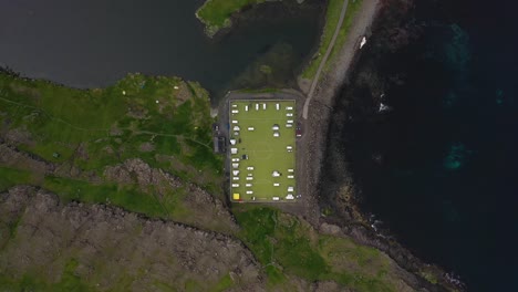 Abandoned-football-pitch-campsite-on-Faroe-Islands-coast,-aerial-birds-eye-view