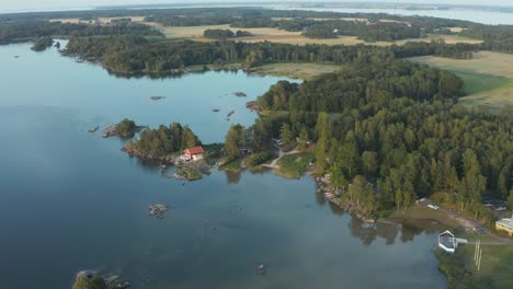 Drohnenaufnahme-Eines-Sees-In-Schweden-Im-Sommer,-Mit-Ein-Paar-Hütten-Im-Blick