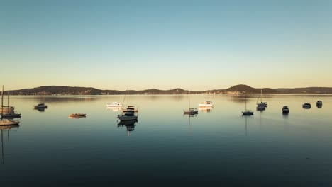 Forward-tracking-aerial-shot-of-some-anchored-boats-during-golden-hour