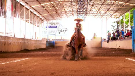 Charros,-Mexican-cowboys-performing-tricks-during-a-Charreada,-a-horse-rider-competition