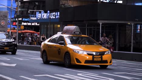 Das-Ikonische-Gelbe-New-Yorker-Taxi-Fährt-Tagsüber-In-Zeitlupe-In-Der-Nähe-Des-Time-Square-Durch-Die-Belebten-Straßen-Manhattans