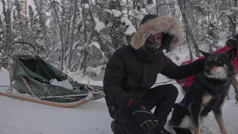 Un-Musher-De-Trineo-Tirado-Por-Perros-Acariciando-A-Un-Perro-Durante-Una-Expedición-En-Trineo