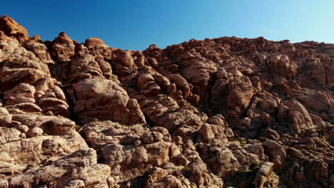 Sweeping-aerial-view-alongside-red-sandstone-mountains-at-Red-Rock-Canyon-Park-near-Las-Vegas,-Nevada