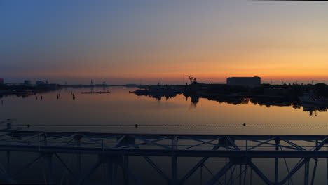 Slow-rising-drone-video-in-the-golden-hour-with-an-old-structure-in-front-of-a-beautiful-sunrise-and-calm-harbour-water-in-Copenhagen