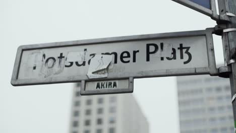 Street-sign-of-Potsdamer-Platz-in-Berlin-with-paper-notes-obscuring-name,-close-up