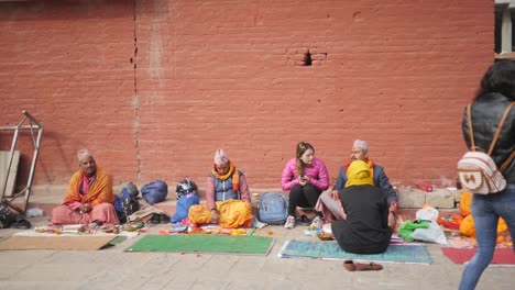 Katmandú,-Nepal---El-Sacerdote-Brahmán-Está-Sentado-En-Fila-Listo-Para-Aceptar-Una-Donación-Y-Dar-Bendiciones-A-Los-Fieles-En-El-Templo