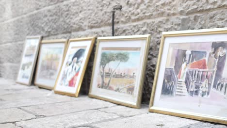 Ground-level,-view-of-legs-of-walking-women-passing-by-paintings-for-sale-in-Jerusalem