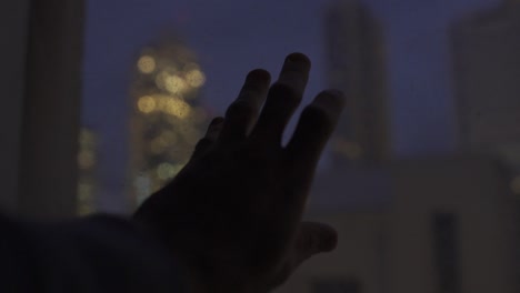 Noche-En-La-Ciudad---La-Mano-Toca-Una-Ventana-Con-Vistas