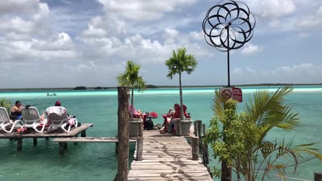 Tourists-Relaxing-on-a-Wooden-Dock-with-a-Breathtaking-view-of-Bacalar-Lagoon-on-a-Summer-Day