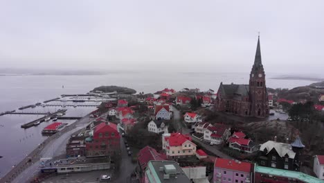 Flying-Over-the-Peaceful-City-in-Lysekil,-Sweden-With-Beautiful-Scenery-of-Exotic-Houses,-church-and-Calm-ocean---Aerial-Shot