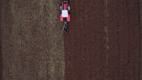 AERIAL:-Top-Down-Shot-of-Red-Tractor-Heavy-Machinery-with-Harrows-Prepares-the-Agricultural-Land-for-Planting-Crop