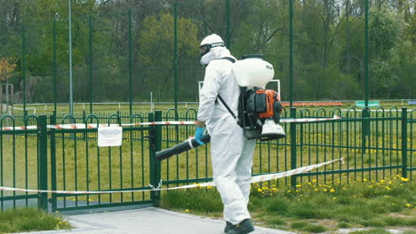 Un-Hombre-Con-Equipo-De-Protección-Desinfecta-Puertas-En-Lugares-Públicos