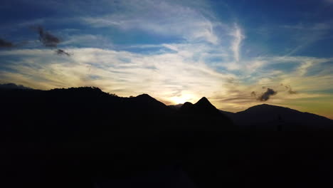 Sombra-Y-Forma-De-La-Montaña-Y-Colinas-Con-Amanecer,-Nubes-Y-Cielo-Azul-Al-Fondo