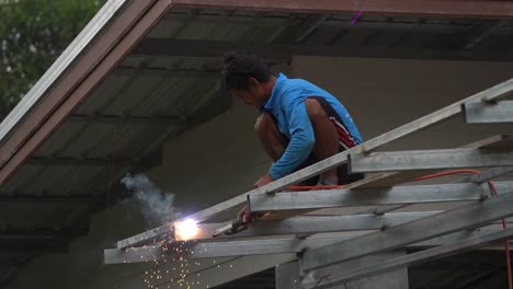 Primer-Plano-En-Cámara-Lenta-De-Un-Joven-Tailandés-Soldando-Un-Techo-Sin-Equipo-De-Seguridad