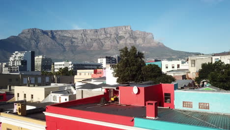 Luftdrohnenaufnahme-Der-Bokaap-Wale-Street-Und-Des-Grünen-Punktes-Zwischen-Der-Strand-Street-Und-Der-Rose-Street-In-Kapstadt,-Südafrika-An-Einem-Sonnigen-Tag-Mit-Blauem-Himmel