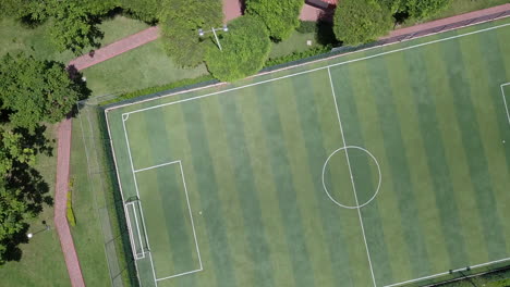 Revealing-straight-down-shot-in-4k-of-empty-mini-soccer-field-surrounded-by-park-and-trees-in-a-gated-community-outside-Guayaquil-City,-Ecuador