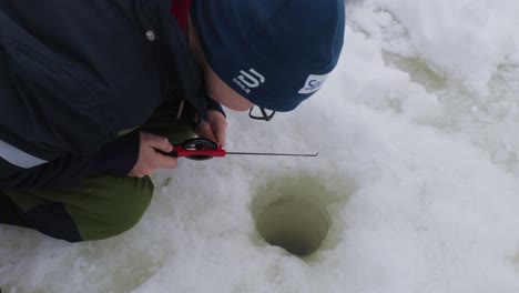 Small-kid-ice-fishing-on-the-frozen-river-in-winter-in-Norway,-View-from-above