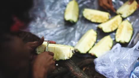 Man-cutting-pieces-of-pineapple-in-the-jungle,-high-shot