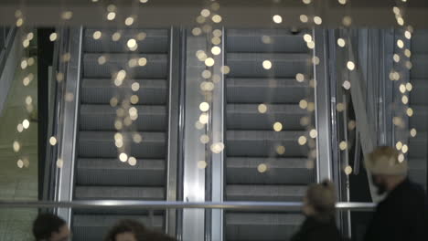 Christmas-lights-hang-as-people-go-up-and-down-on-a-public-escalator