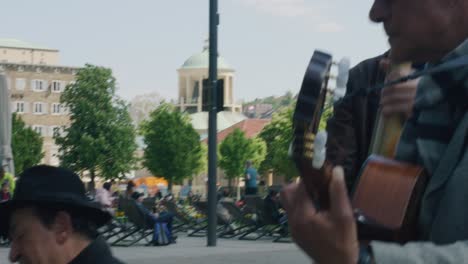 Three-street-musicians-playing-instruments-in-downtown-Stuttgart-square-at-noon,-Germany,-Europe,-panning-view-angles