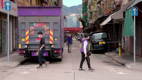 Asiatische-Einheimische-Laufen-über-Die-Straße-Und-Tragen-Einkaufstüten,-Im-Hintergrund-Die-Hochmoderne-Stadt-Hongkong