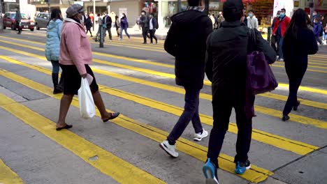 Crowd-of-people-crosses-Hong-Kong-street-on-yellow-crosswalk