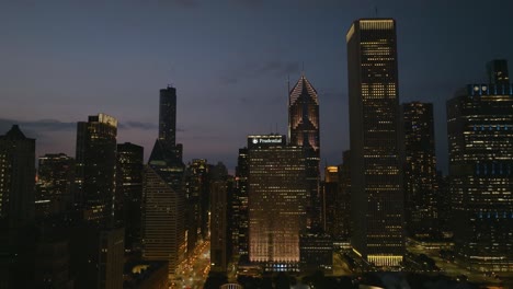 Vista-Aérea-Frente-A-Rascacielos-Iluminados-En-El-Nuevo-Lado-Este-De-Chicago,-EE.UU.---Seguimiento,-Disparo-De-Drones