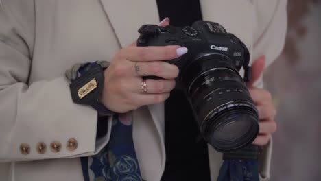 A-mirrorless-camera-in-hands-of-a-female-photographer-while-she's-explaining-how-to-pose-for-pictures,-photographer-routine,-close-up-shot