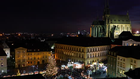 Mercado-Navideño-Dominante-En-Brno-En-Zeleny-Trh-Durante-La-Noche-Vista-De-Mercados-Enteros-Con-Puestos-Y-árboles-De-Navidad-E-Iglesias-En-El-Fondo-Capturados-En-Cámara-Lenta-De-4k-60fps