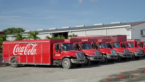 Row-Of-Stationary-Parked-Coca-Cola-Trucks-At-Distribution-Centre-In-Punta-Cana,-Dominican-Republic