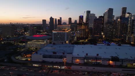 Aerial-view-over-traffic,-towards-the-Hilton-Americas-and-the-Toyota-center-in-Houston,-dusk-in-Texas,-USA