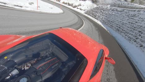 Ferrari-tackling-steep-corners-on-a-mountain-road-surrounded-by-snow