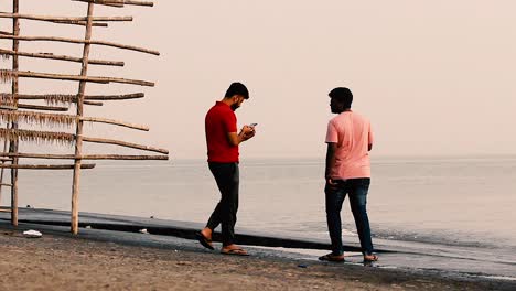 A-boy-clicking-a-picture-of-his-friend-near-a-beach-shore-during-sunset-enjoying-holidays-video-background-in-HD-in-mov