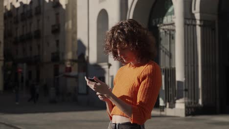 Hübsche-Lockige-Frau,-Die-Im-Europäischen-Stadtzentrum-Ein-Smartphone-Foto-Macht