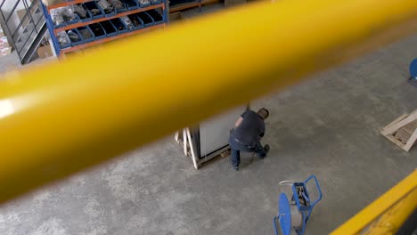 Worker-wrapping-protective-black-plastic-film-on-solar-panel-crate-for-shipping,-View-from-above