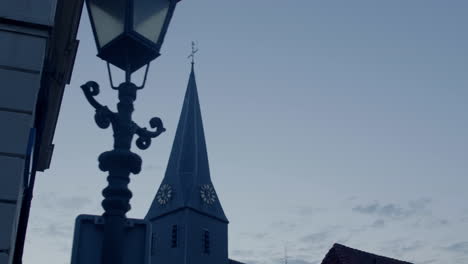 Reveal-shot-passing-by-a-streetlight-revealing-the-church-behind-it-in-the-early-morning-dawn