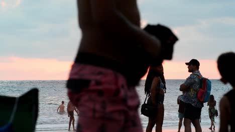 überfüllter-Strand-Bei-Sonnenuntergang-Mit-Mehreren-Personen-Im-Bokeh-Vordergrund