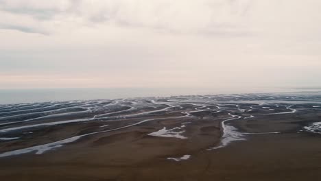 Aerial-drone-landscape-clip-over-a-river-delta-running-down-to-the-ocean-with-swamp-like-formations-in-Southport,-UK