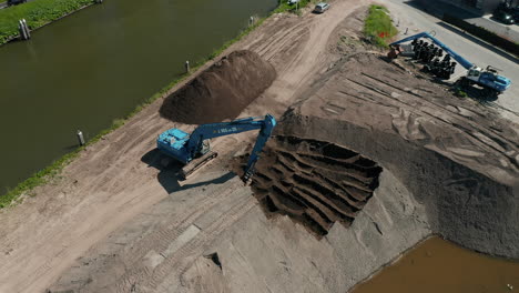 An-Excavator-Digging-And-Moving-Some-Sand-Beside-The-Gouwe-Canal,-South-Holland,-Netherlands