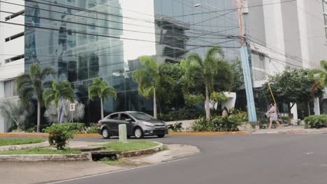 Pan-view-from-right-to-left-of-city-crossroads-with-traffic-lights,-road-markings,-sidewalk-for-pedestrians,-with-cars-and-people