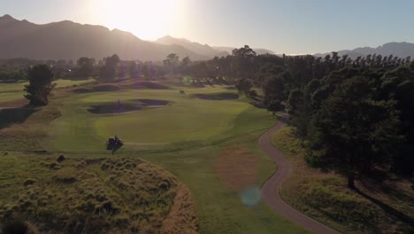 Aerial-Drone-View-of-Pearl-Valley-Golf-Estate-Golf-Course-in-South-Africa-on-Sunset,-Rich-Green-Turf-and-Sand-Bunkers,-Golfers-Walking-on-a-Field,-Staff-Prepare-Golf-Field,-Cutting-Green-Grass