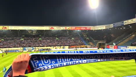 En-El-Estadio-De-Fútbol-Del-FC-Hansa-Rostock,-Los-Aficionados-Escuchan-Cánticos-Poco-Antes-Del-Inicio-Del-Partido.