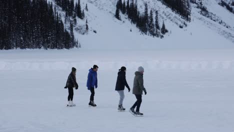 Winter-sports,-tourists-skating-on-frozen-lake-Louise,-Snowy-landscape