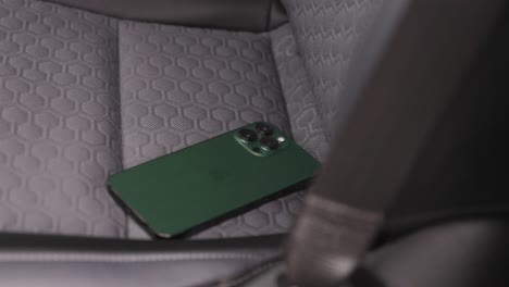 turbulent-video-of-a-white-hand-with-a-blue-sleeve-reaching-to-grab-an-alpine-green-apple-iphone-off-a-truck-seat