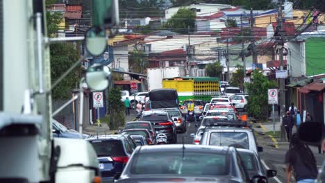 SAN-JOSÉ,-COSTA-RICA---FEBRUARY-6,-2022:-many-cars-slowly-moving-in-the-traffic,-with-a-smart-man-on-a-skateboard-going-faster-than-anyone-else